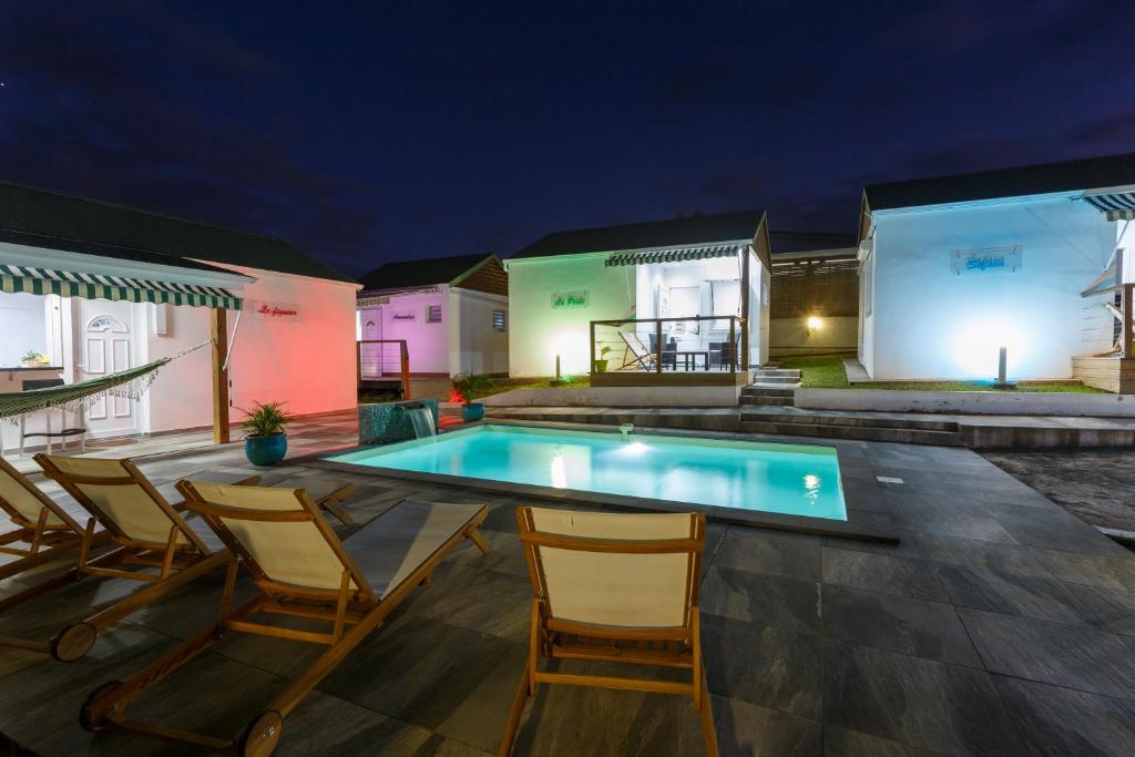 a patio with chairs and a swimming pool at night at Domaine de Sainval in Sainte-Rose