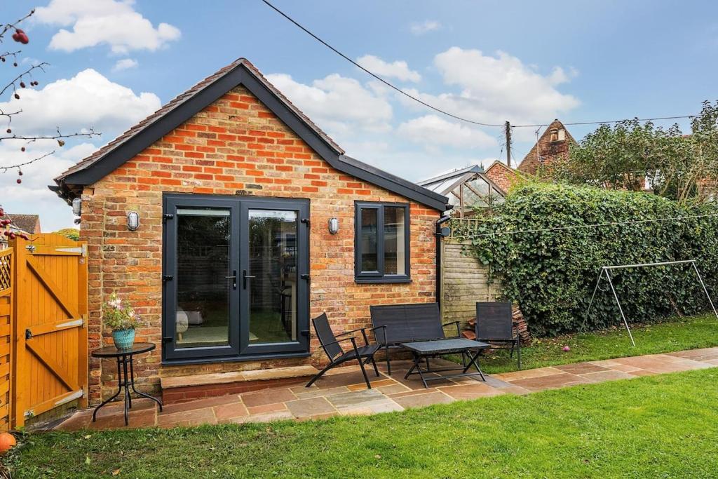 a small brick house with a table and chairs at Cottage in the heart of award-winning English village in Woodchurch
