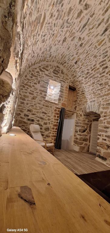 Cette chambre est dotée d'un mur en pierre avec une table et des chaises. dans l'établissement Maison blanche, à Saint-Étienne-du-Valdonnez