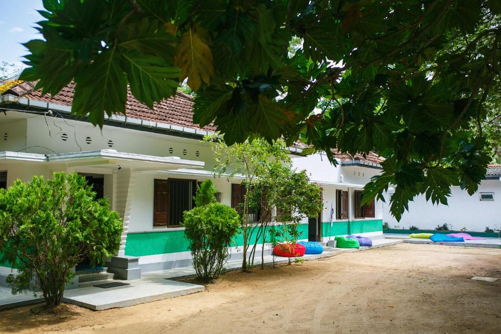 a white building with trees in front of it at Hostel First Mirissa in Mirissa