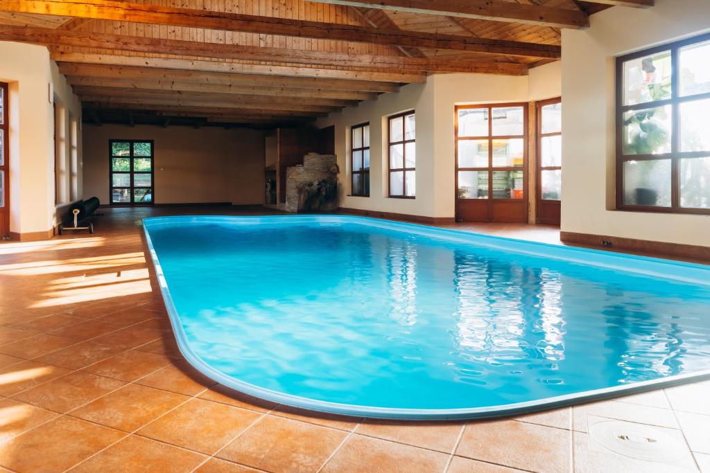 a large pool with blue water in a room with windows at Penzion Pod Chřiby in Zdounky