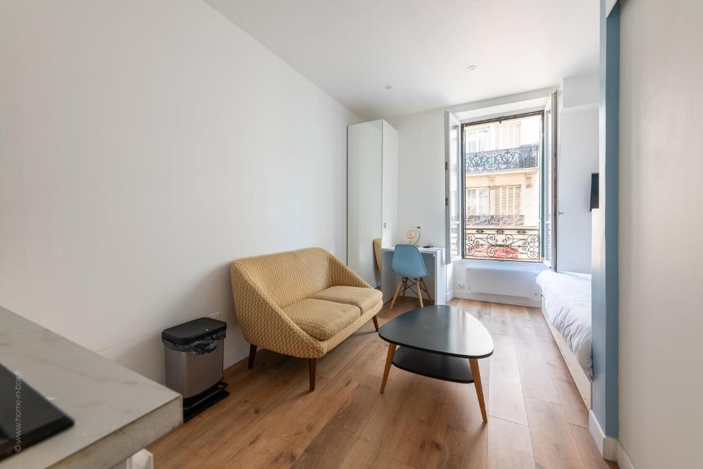 Una sala de estar con una silla y una mesa. en Studio lumineux proche Paris Vincennes, en Saint-Mandé