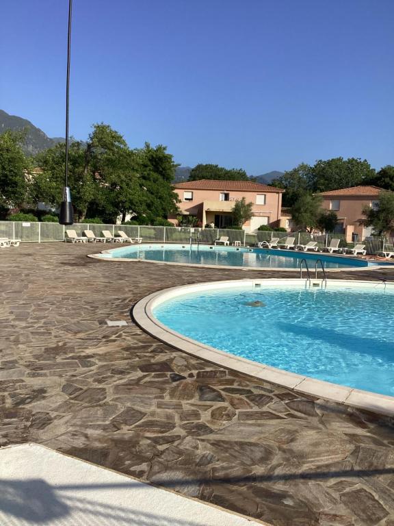 - une grande piscine avec des chaises dans un complexe dans l'établissement Santa Maria Poggio, à Moriani-Plage