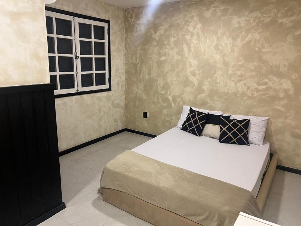 a bedroom with a bed and a window at Casa estilosa na rua principal de Búzios in Búzios