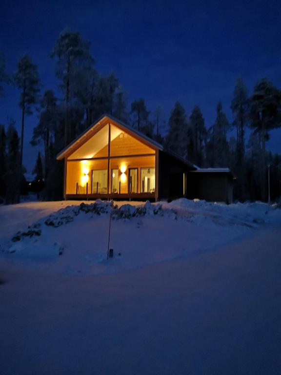 a house lit up in the snow at night at Kiiruna Chalet in Kuusamo