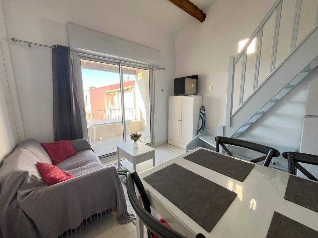 un salon avec un canapé et une table dans l'établissement Appartement T3 avec Piscine, Climatisation et Parking à 350m de la Plage - Capacité 4 Personnes - FR-1-749-34, au Cap d'Agde