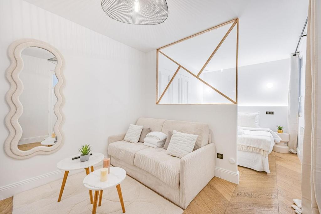 un salon blanc avec un canapé et un miroir dans l'établissement Suite luxueuse Elysee Faubourg St Honore Paris 8, à Paris