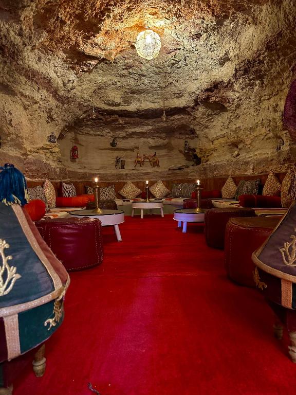 a room with couches and red carpet in a cave at Kasbah El Hajja in Aït Benhaddou