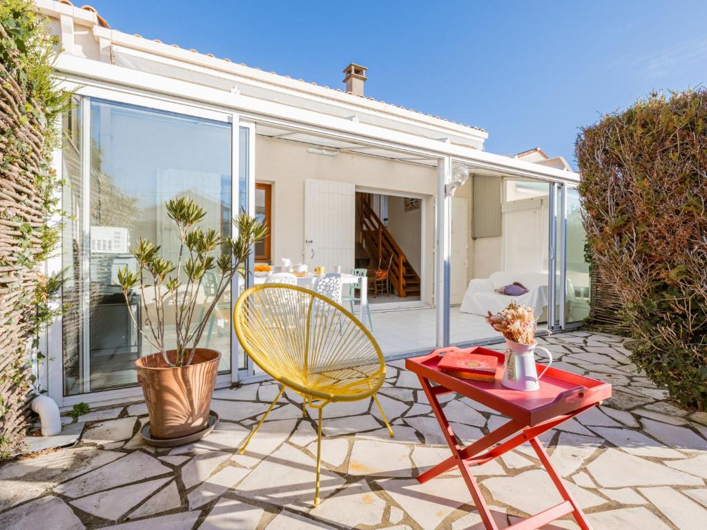 d'une terrasse avec une table rouge et une chaise jaune. dans l'établissement Holiday Home Fief des Taillis by Interhome, à Vaux-sur-Mer