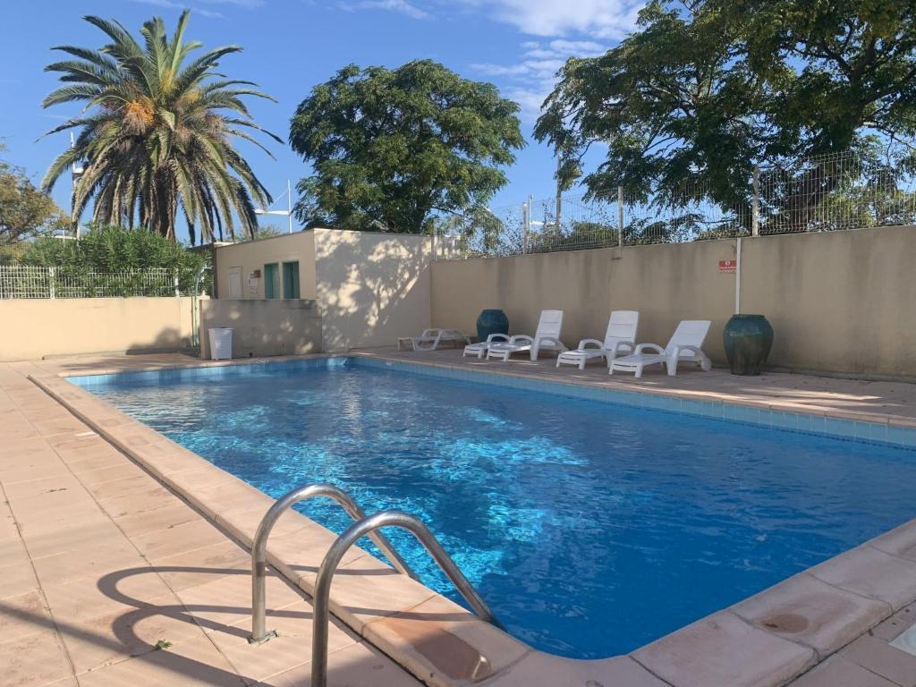 une piscine avec des chaises à côté d'une clôture dans l'établissement Apartment La Palme d'Or-21 by Interhome, à Agde