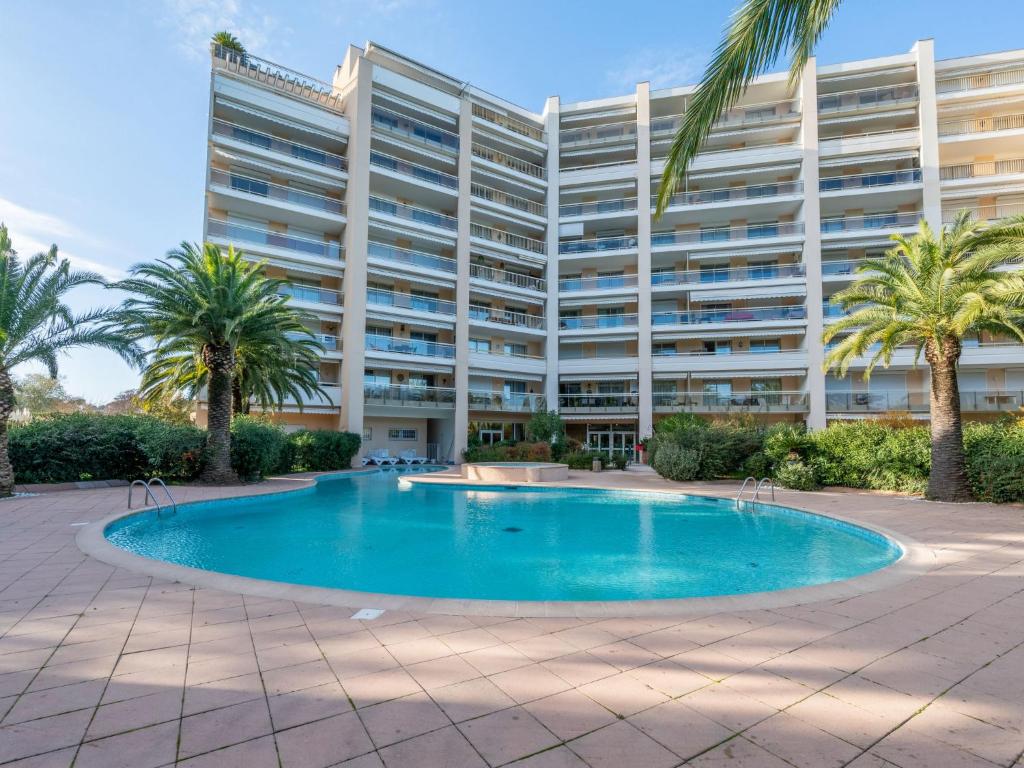 un grand immeuble avec piscine et palmiers dans l'établissement Apartment Résidence des Golfeurs by Interhome, à Mandelieu-la-Napoule
