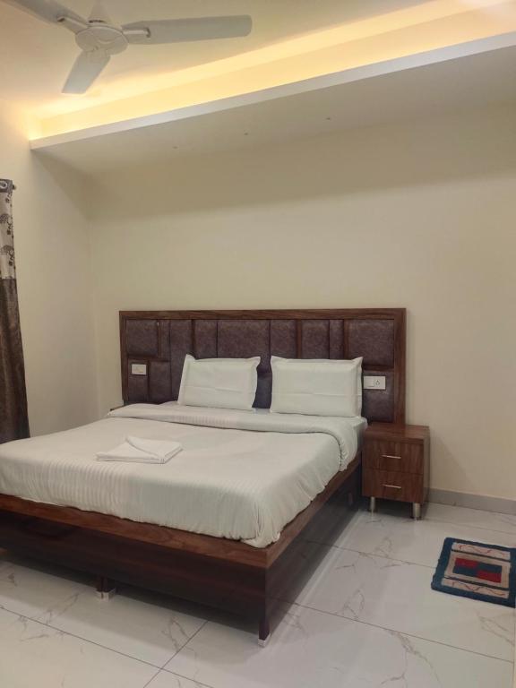 a bedroom with a large wooden bed with white sheets at Hotel G-3 in Jalandhar