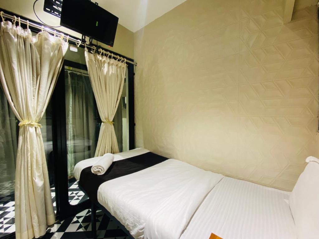 a bedroom with a bed and a window with curtains at Sulu Stay Inn Near Mumbai International Airport in Mumbai