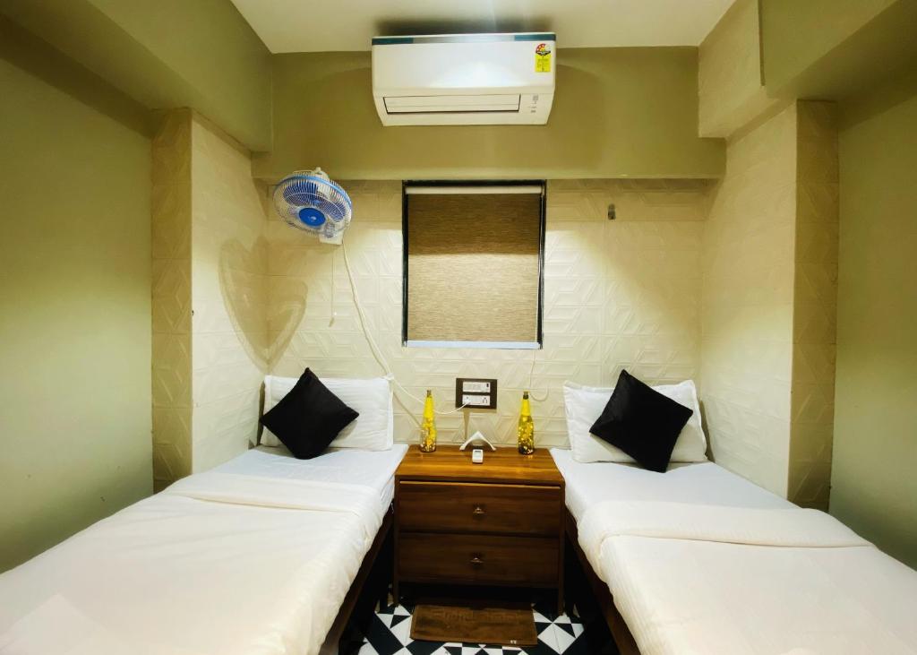 two twin beds in a room with a fan at Sulu Stay Inn Near Mumbai International Airport in Mumbai