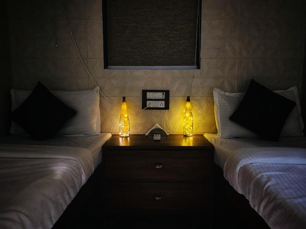 two beds in a room with two lamps on a table at Sulu Stay Inn Near Mumbai International Airport in Mumbai