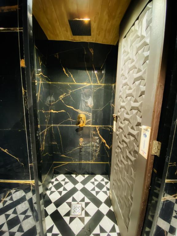 a bathroom with a black wall and a black and white tile floor at Sulu Stay Inn Near Mumbai International Airport in Mumbai