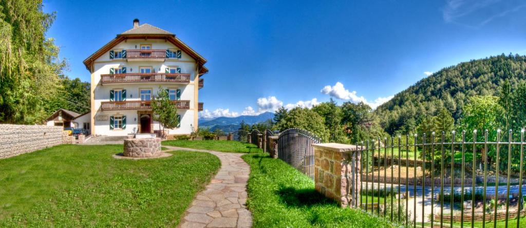 ein Haus in den Bergen mit einem Zaun in der Unterkunft Apartments Waldquell in Klobenstein