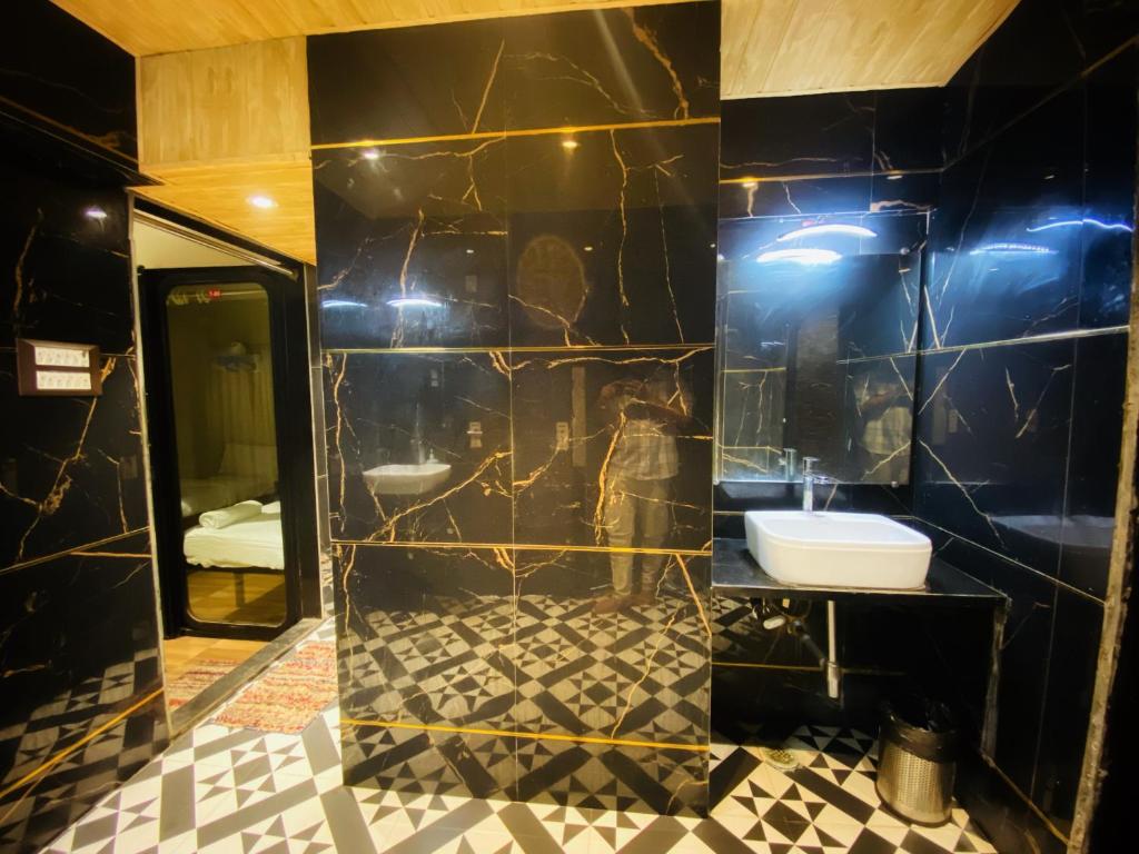 a black bathroom with a sink and a mirror at Sulu Stay Inn Near Mumbai International Airport in Mumbai