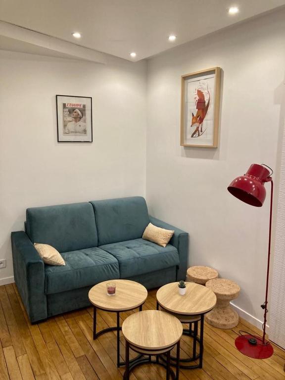 un salon avec un canapé bleu et deux tables dans l'établissement Appartement Paris 15, à Paris