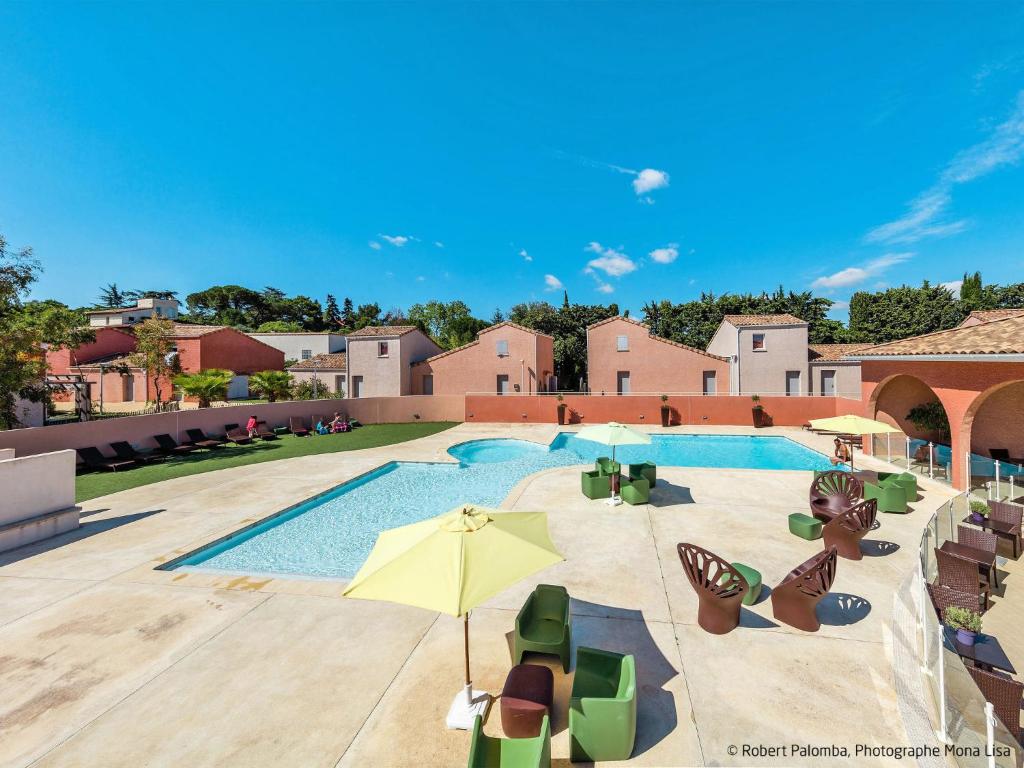une piscine avec chaises et parasols sur un immeuble dans l'établissement Holiday Home Domaine de Bacchus-Séjour-Galerie 4 pers by Interhome, à Saint-Christol