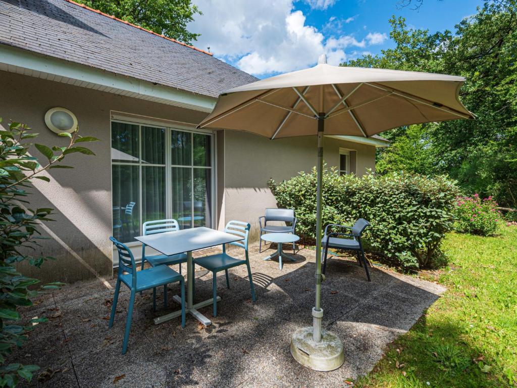 a table and chairs under an umbrella in a yard at Holiday Home Cottage Privilège-1 by Interhome in Saumur