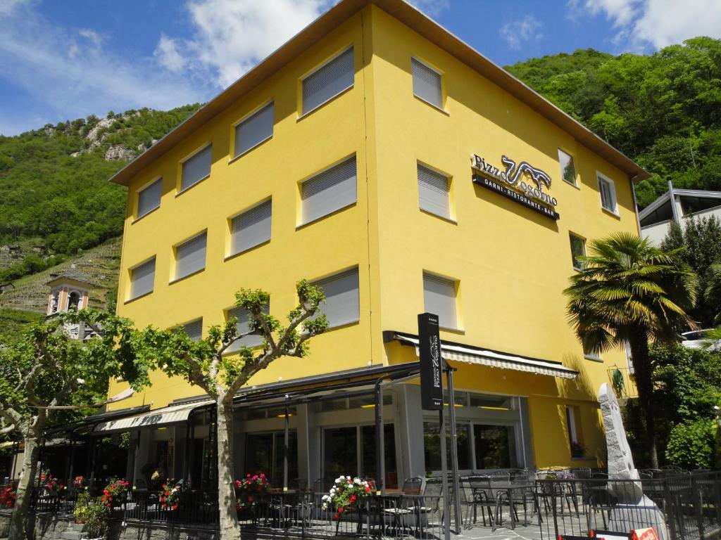 a yellow building with tables and chairs in front of it at Hotel Pizzo Vogorno in Vogorno