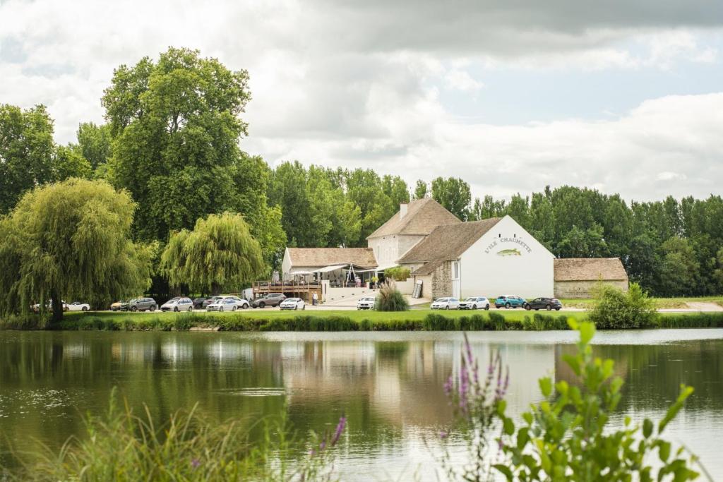 un grand bâtiment blanc à côté d'un lac dans l'établissement L'ile chaumette, à Épervans