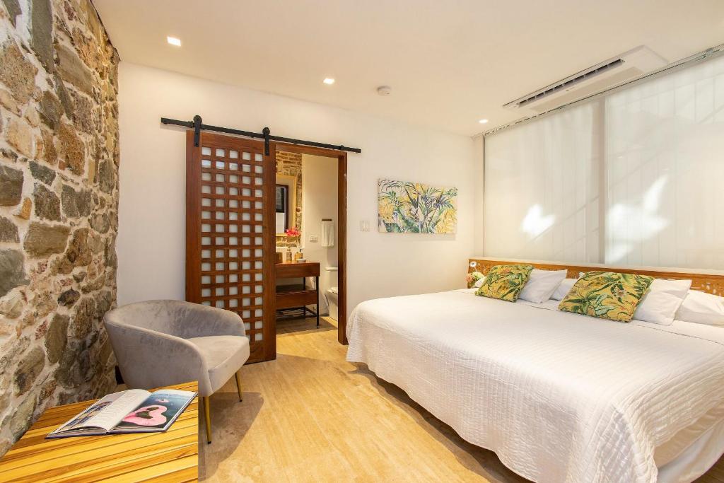 パナマシティにあるVillas La Fontana Amplias ApartaSuite-piscina 103のベッドと石の壁のある寝室