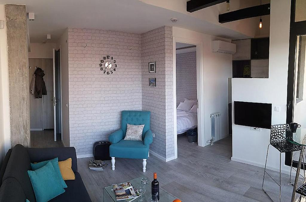 un soggiorno con sedia blu e una camera da letto di Apartment Savamala Art a Belgrado