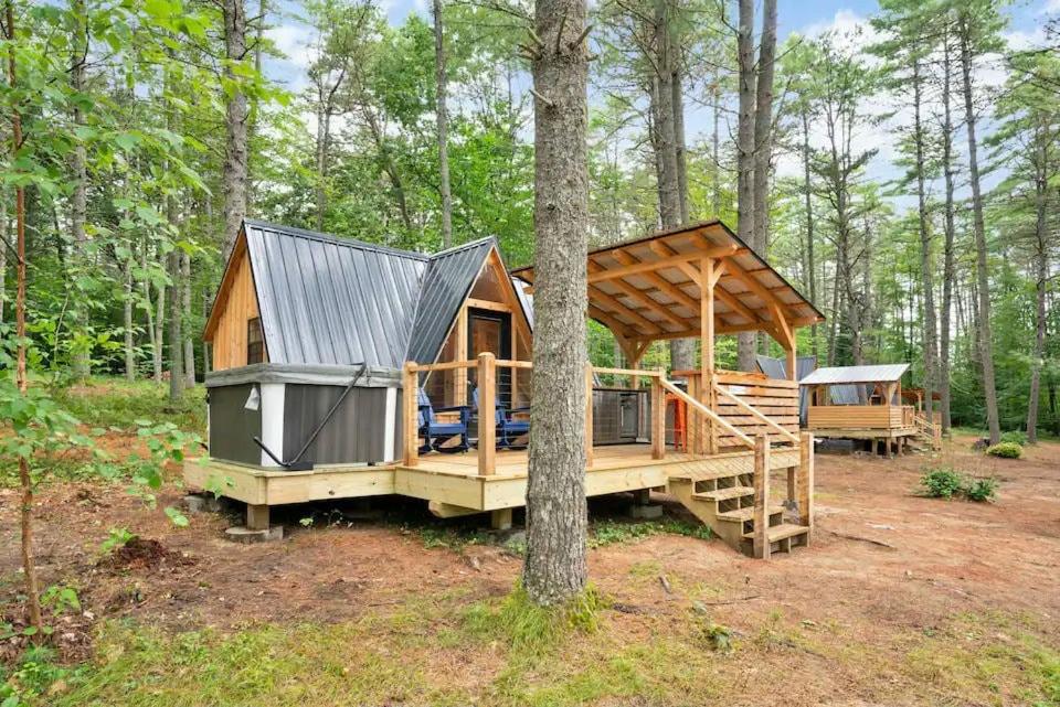 a large wooden cabin in the woods with a tree at A-Frame Retreat with Inviting Hot Tub in Oxford