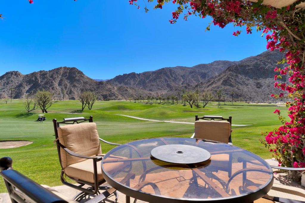 a glass table and chairs with a view of a golf course at Golf Course Villa with Exceptional Views in La Quinta
