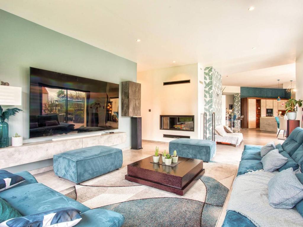 Elle comprend un salon doté d'un mobilier bleu et d'une cheminée. dans l'établissement Maison élégante avec jacuzzi, confort moderne et histoire à Ranville - FR-1-788-44, à Ranville