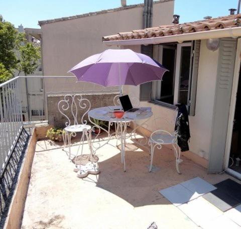 d'une terrasse avec une table et un parasol violet. dans l'établissement Studio terrasse hyper center, à Avignon