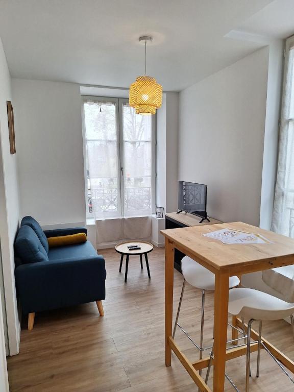 un salon avec une table et un canapé bleu dans l'établissement Notre Dame 3 - Très belle vue sur la Loire - Lumineux - Hypercentre, à Orléans