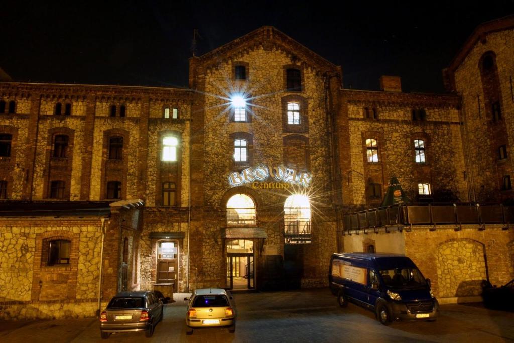 two cars parked in front of a building at night at Centrum Browar in Strzelce Opolskie