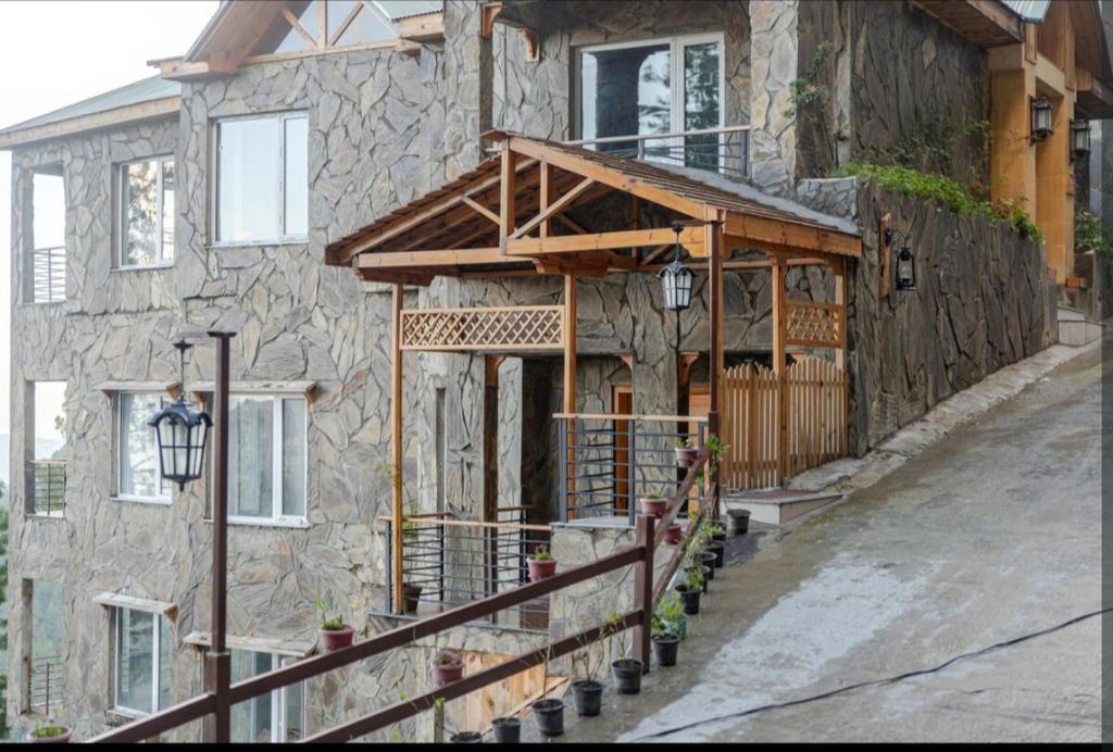 a stone house with a porch and a wooden door at Scenic Apartment in Khaira Gali in Abbottābād