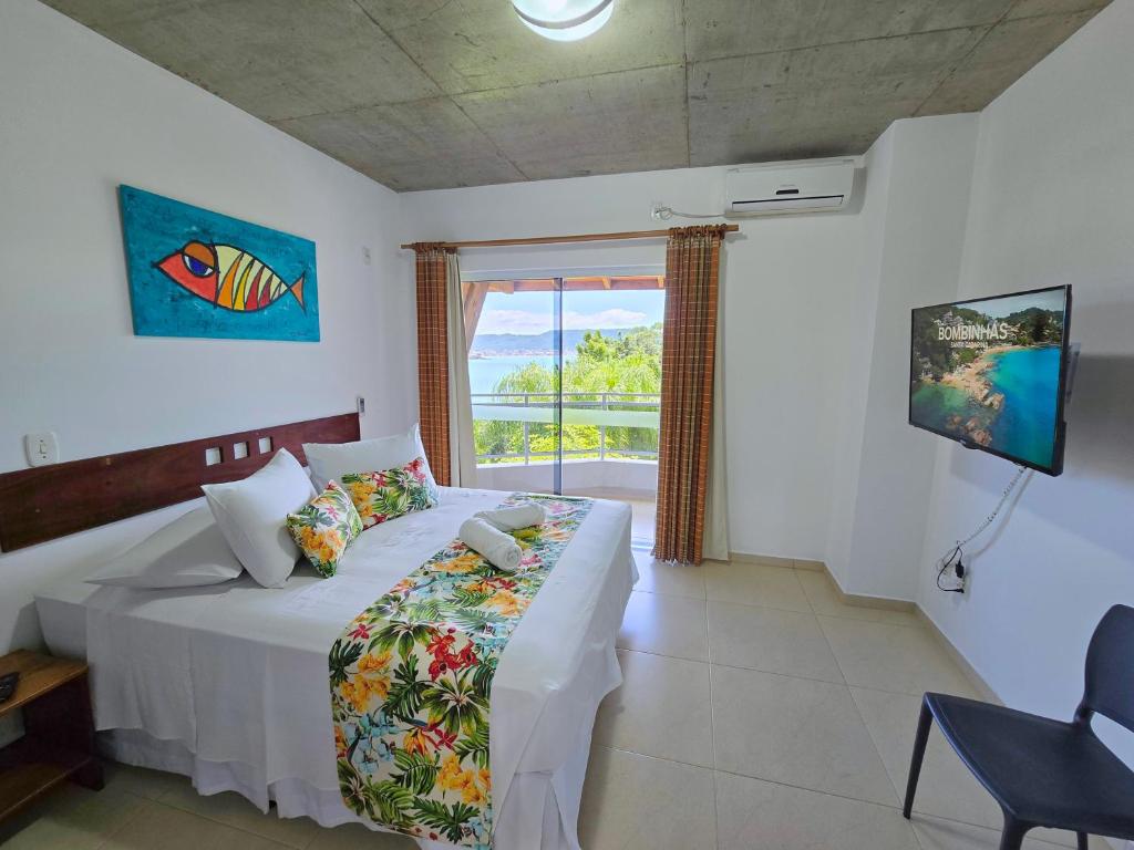 a bedroom with a bed and a large window at Refúgio da Lagoinha - Centro de Bombinhas in Bombinhas