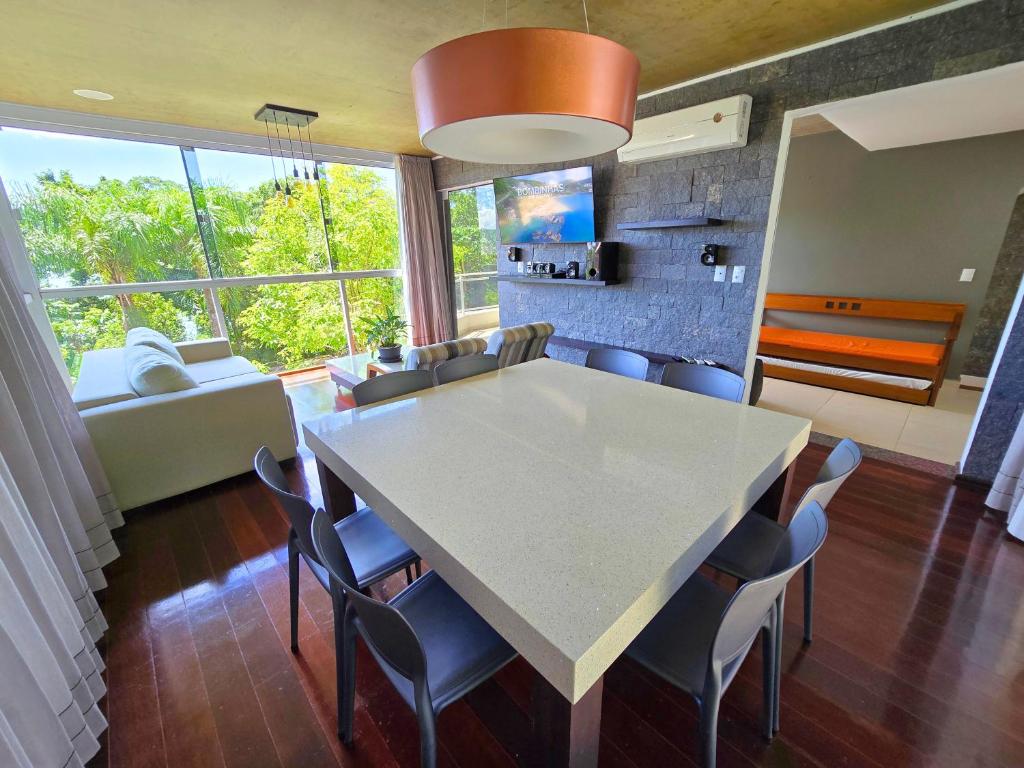 a kitchen and dining room with a white table and chairs at Refúgio da Lagoinha - Centro de Bombinhas in Bombinhas