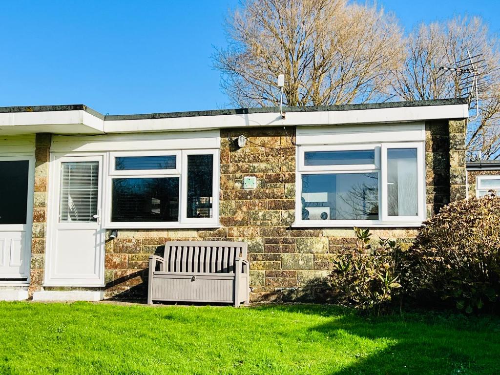 a brick house with a bench in the grass at 2 Bedroom Chalet SB172, Sandown Bay, Isle of Wight, Free WiFi in Isle of Wight