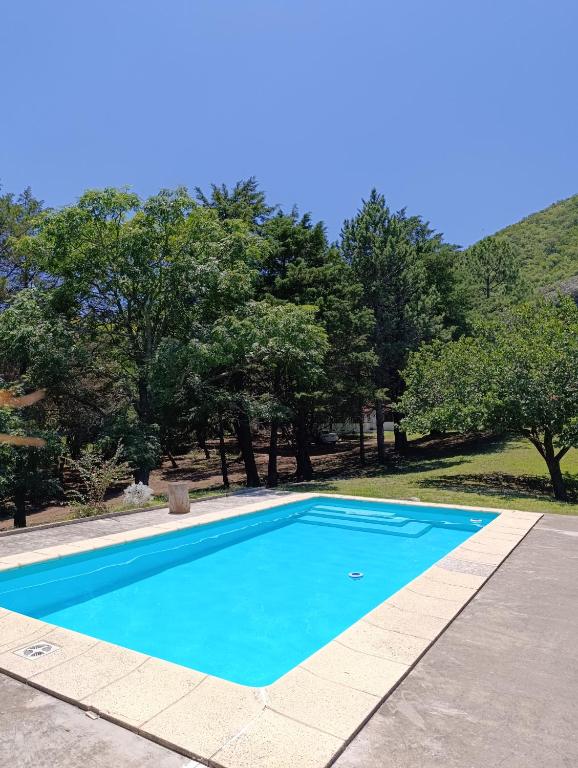 a blue swimming pool with trees in the background at Hermosa Casa V. General Belgrano in Villa General Belgrano