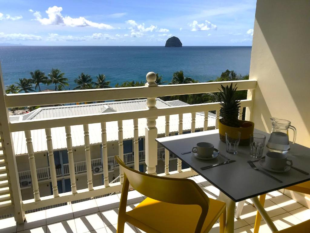 a balcony with a table and chairs and the ocean at Ti studio coquet vue mer 180 degrés face Diamant, piscine de standing in Le Diamant