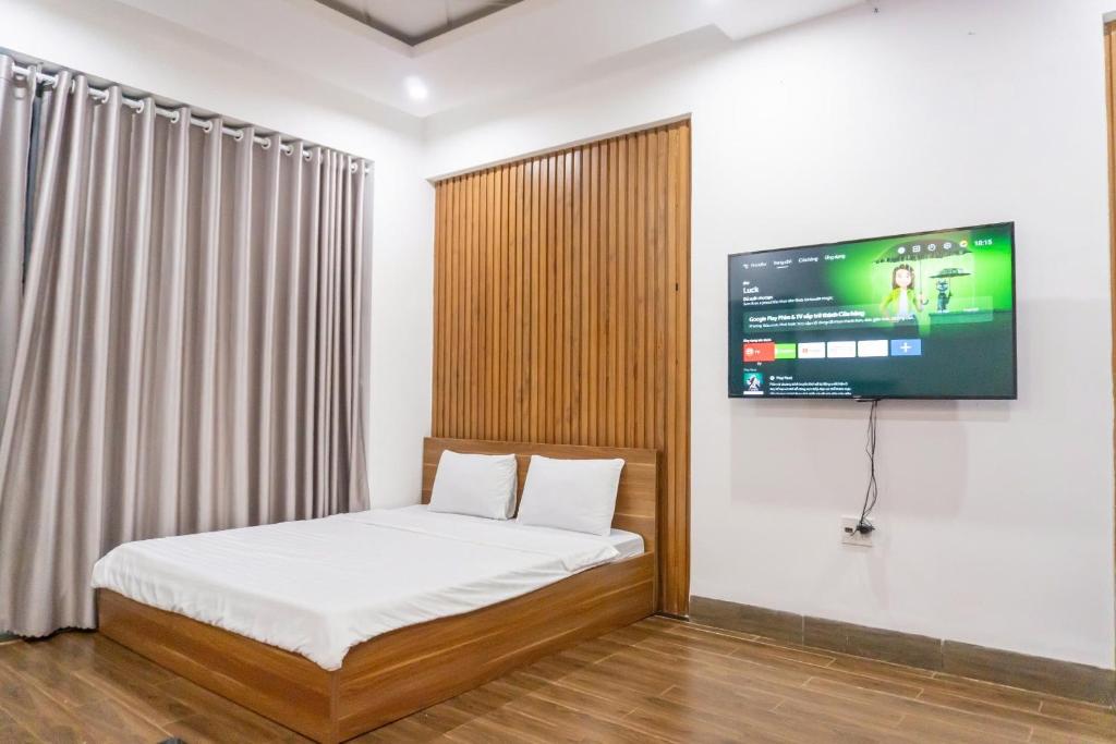 a bedroom with a bed and a tv on a wall at Cherry homestay bmt phòng đôi gia đình in Buôn Ðũng
