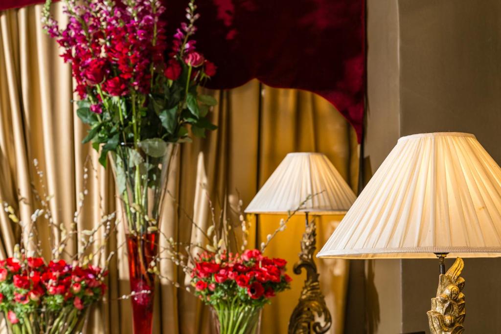 two vases filled with red flowers next to two lamps at Le Cavendish in Cannes