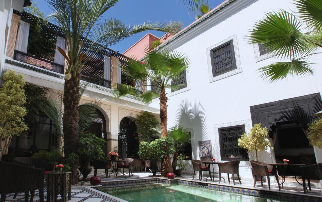 een binnenplaats van een huis met een zwembad en palmbomen bij Riad Monceau in Marrakesh