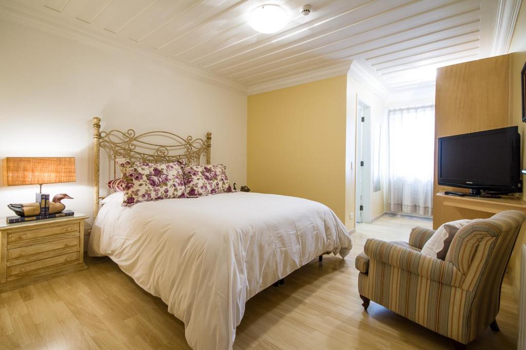 a bedroom with a bed and a television at Pousada Casa Gialla in Campos do Jordão
