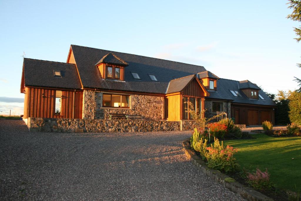 a large wooden house with a stone driveway at Tarskavaig Bed & Breakfast in Radernie