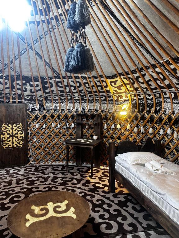 a room with a bed and a table in a yurt at Ethnochill Karakol yurt camping in Karakol