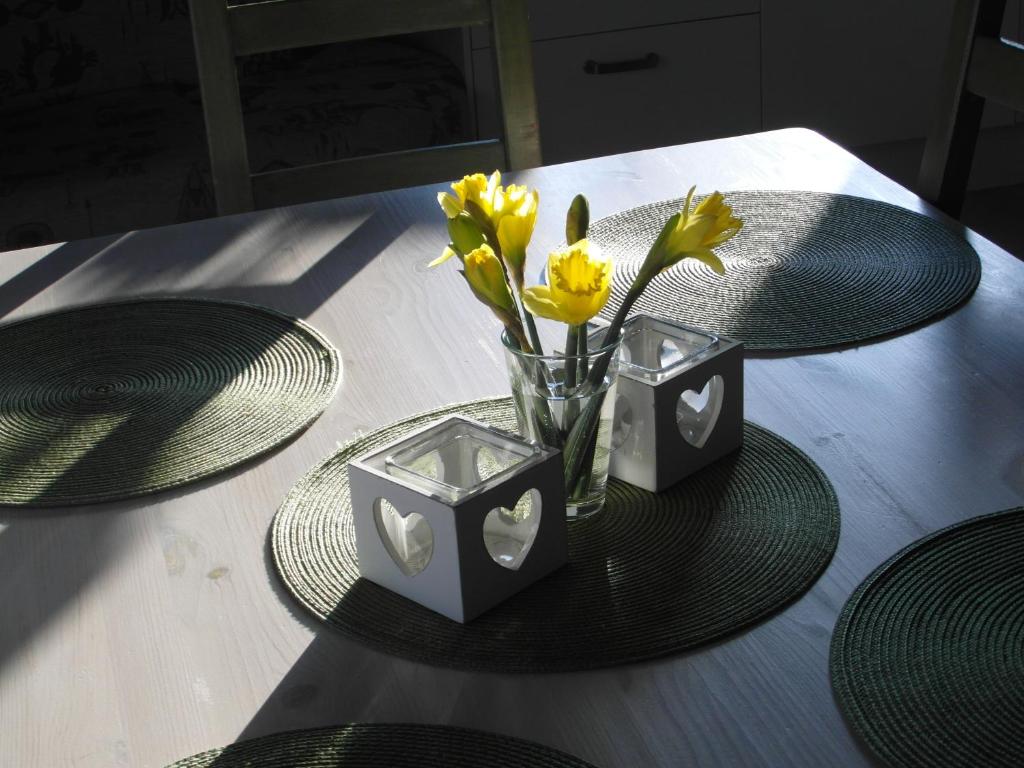 una mesa con dos platos y un jarrón con flores amarillas en Apartamenty Nad Zalewem en Nieporęt