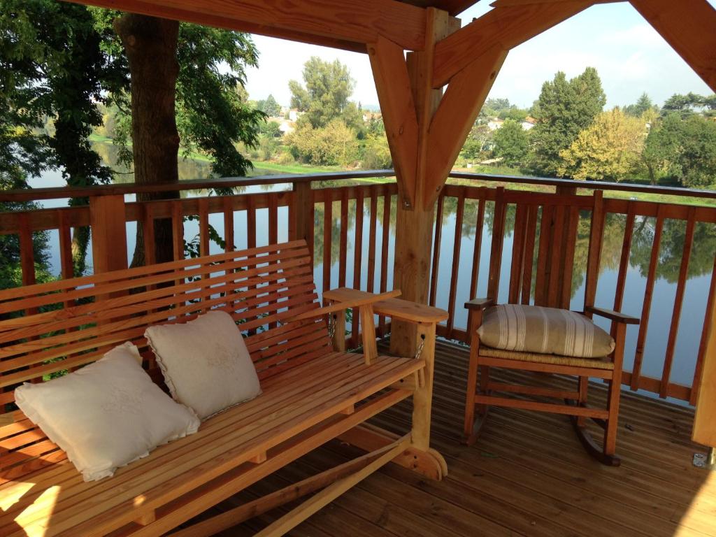 un banc en bois assis sur une terrasse avec une chaise dans l'établissement Along The River, à Bergerac