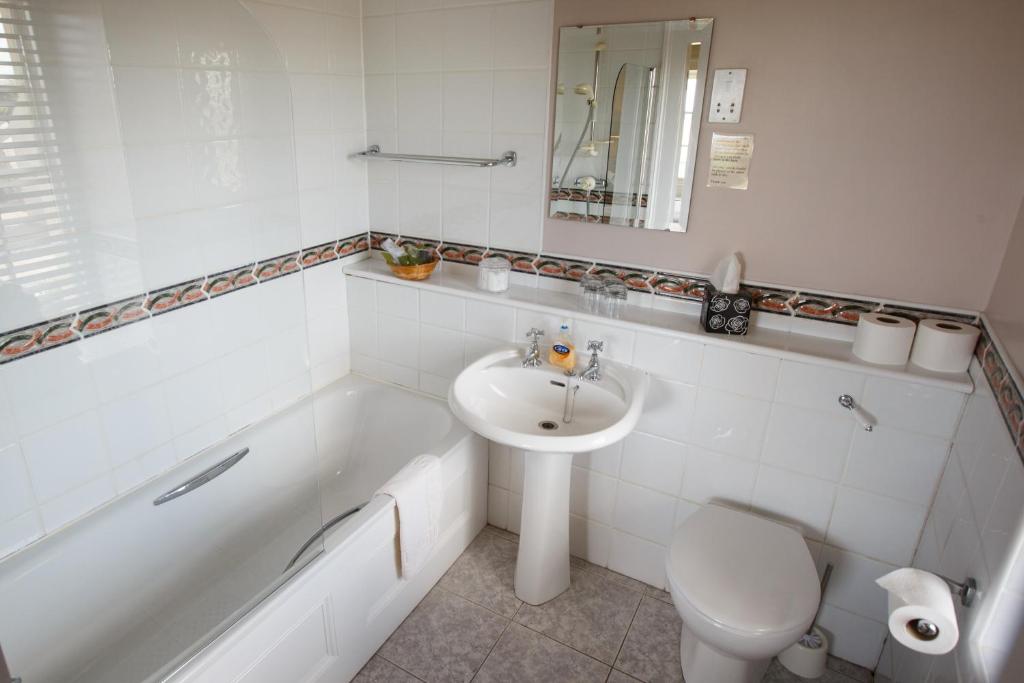 a bathroom with a sink and a tub and a toilet at Portclew House in Pembroke